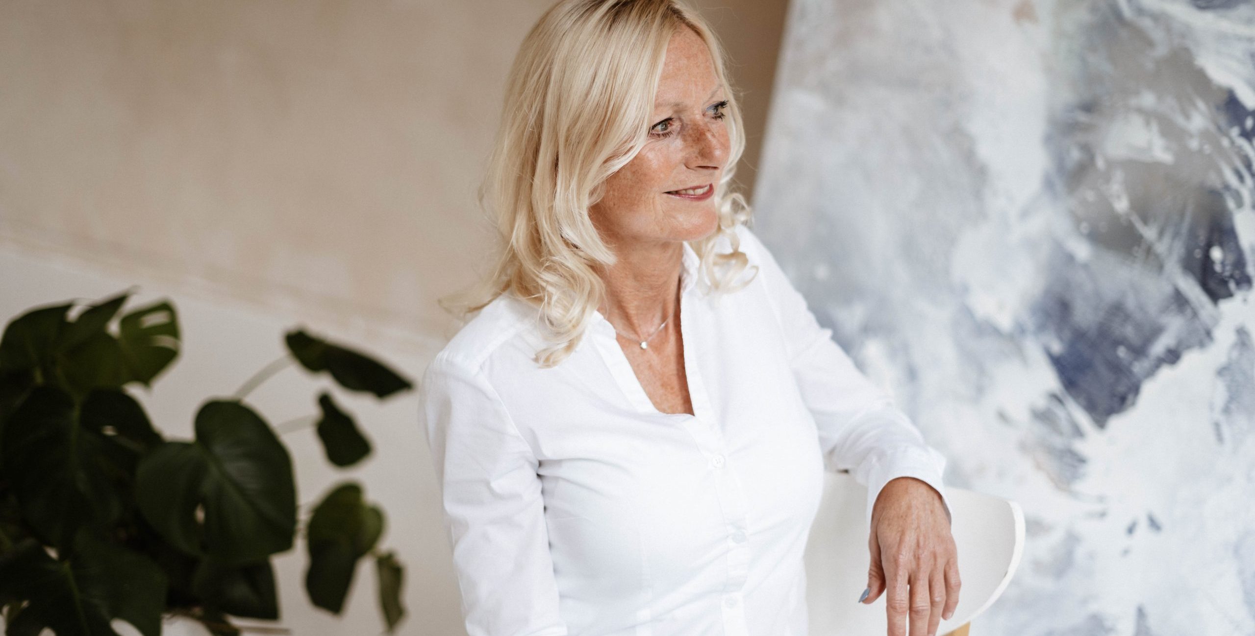 Vrouw zit lachend en kijkt rechts langs de camera Vrouw zit lachend en kijkt rechts langs de camera